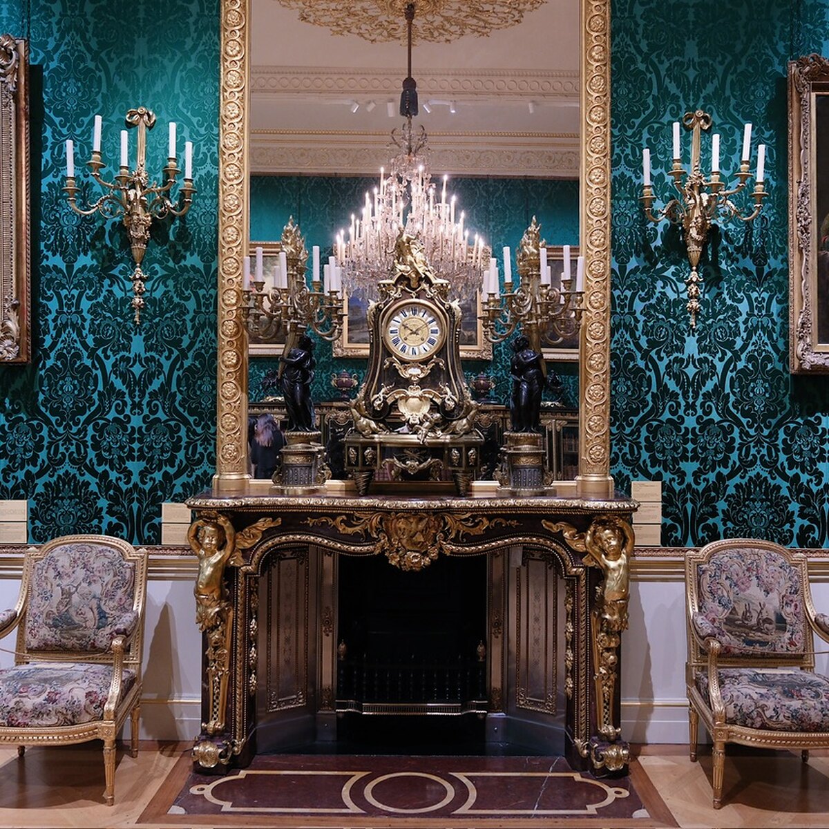 A teal-walled room at the Wallace Collection, with a gilded fireplace, chandelier and chairs